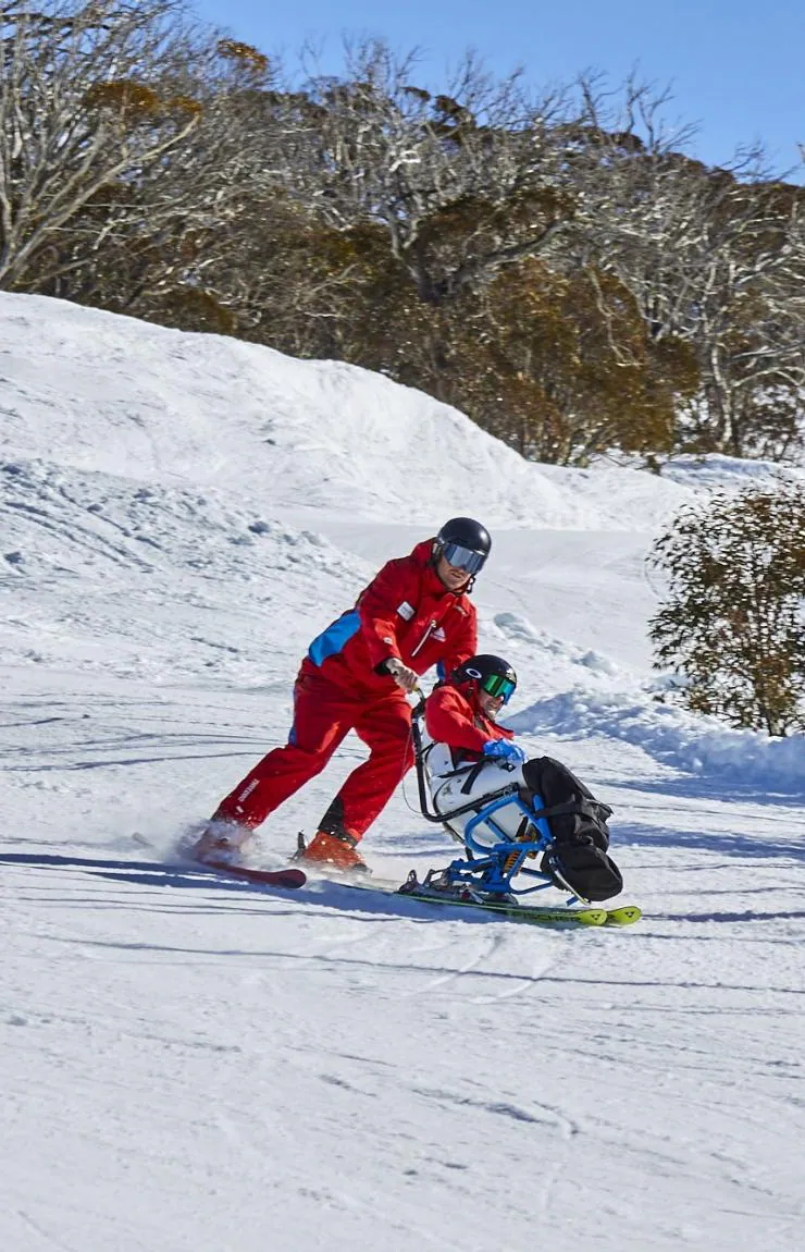 Two people with limited mobility adaptive skiing with instructors down a snow-covered mountain in Thredbo, Snowy Mountains, New South Wales © Tourism Australia 澳洲168幸运5官方开奖结果 官方澳洲幸运5